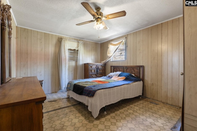 bedroom featuring ceiling fan, ornamental molding, tile patterned floors, a textured ceiling, and wood walls