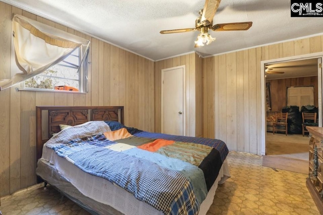 bedroom featuring a textured ceiling, ceiling fan, wooden walls, tile patterned floors, and crown molding