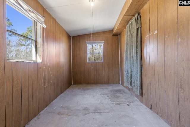 spare room with wood walls and unfinished concrete floors