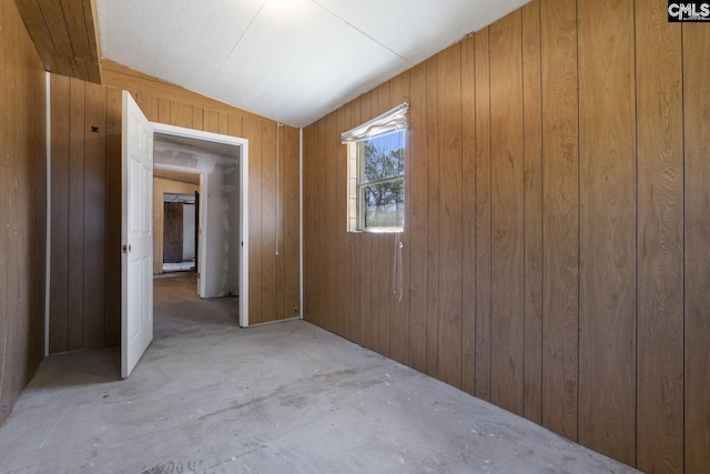 spare room with wood walls and unfinished concrete flooring