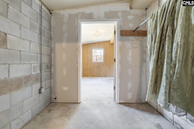 interior space featuring concrete block wall and unfinished concrete floors