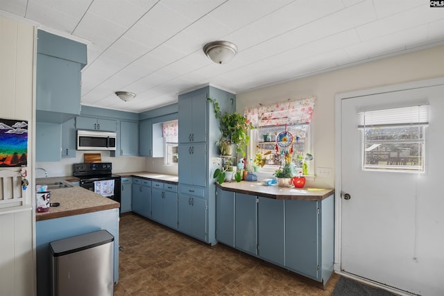 kitchen featuring electric range, stainless steel microwave, blue cabinets, light countertops, and a sink