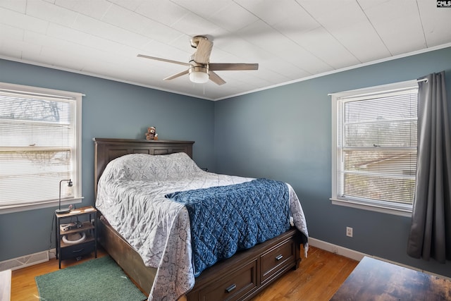 bedroom featuring crown molding, wood finished floors, and baseboards