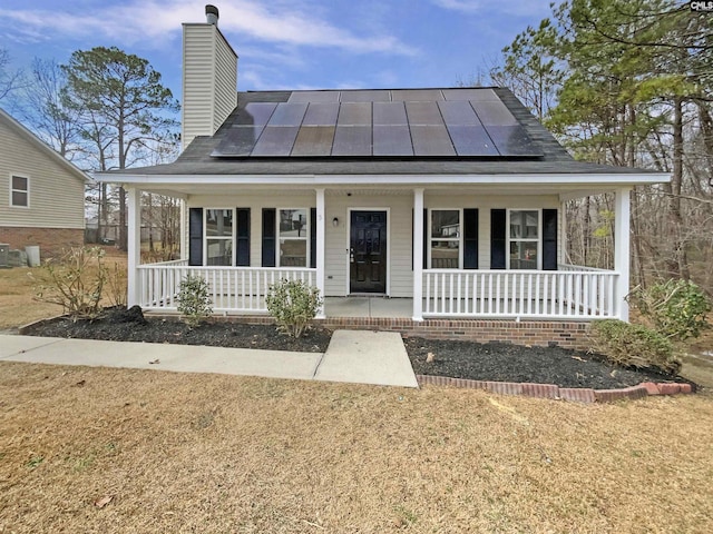 view of front of property with a porch, a standing seam roof, and solar panels