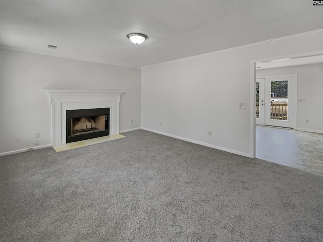 unfurnished living room with a fireplace with flush hearth, visible vents, a textured ceiling, and carpet flooring