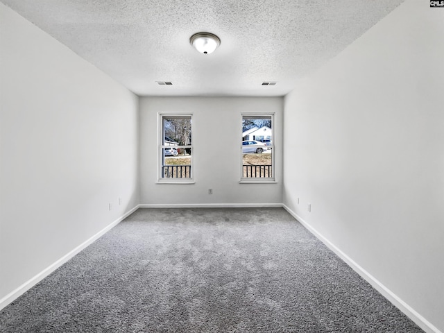 unfurnished room with carpet, visible vents, and baseboards