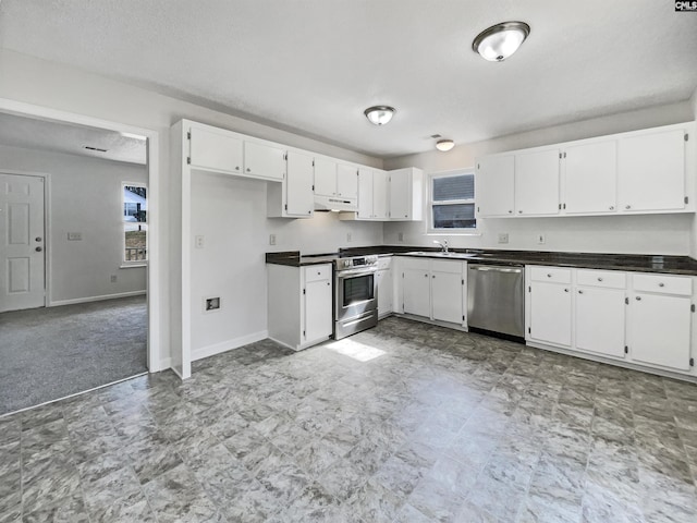 kitchen featuring dark countertops, under cabinet range hood, white cabinets, and stainless steel appliances