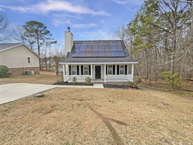 view of front of house featuring central AC unit, covered porch, solar panels, a front lawn, and a chimney