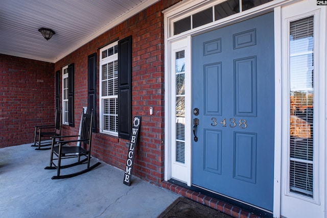 property entrance featuring covered porch and brick siding