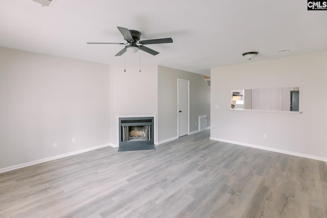 unfurnished living room featuring ceiling fan, wood finished floors, a fireplace with flush hearth, and baseboards