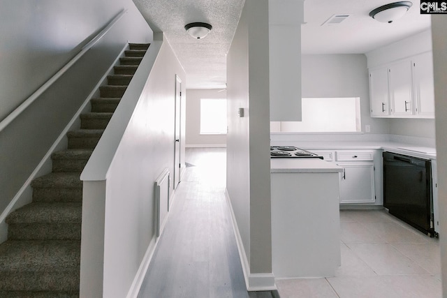 kitchen featuring light countertops, visible vents, white cabinets, a textured ceiling, and black appliances