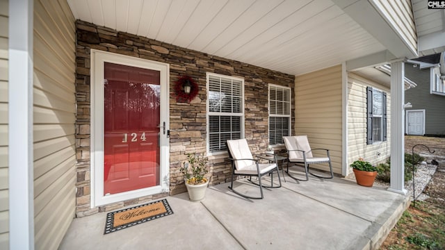 entrance to property featuring a porch and stone siding