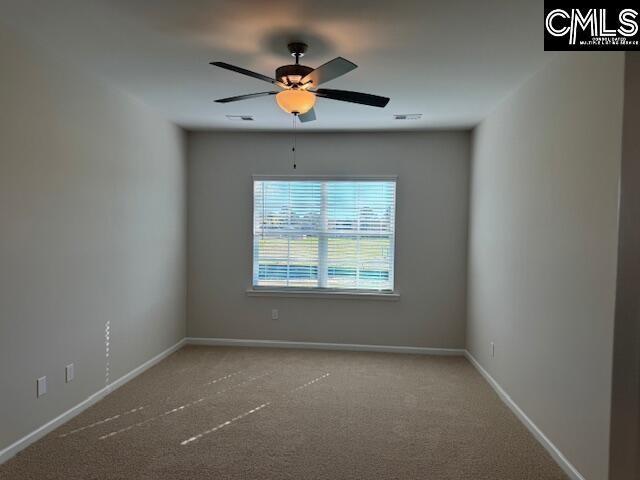 carpeted spare room featuring visible vents, a ceiling fan, and baseboards