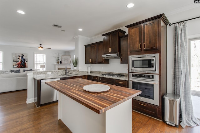 kitchen with visible vents, butcher block counters, a peninsula, stainless steel appliances, and a sink