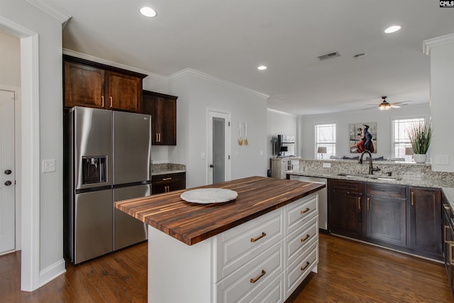 kitchen with stainless steel appliances, dark wood-type flooring, a sink, wood counters, and dark brown cabinets