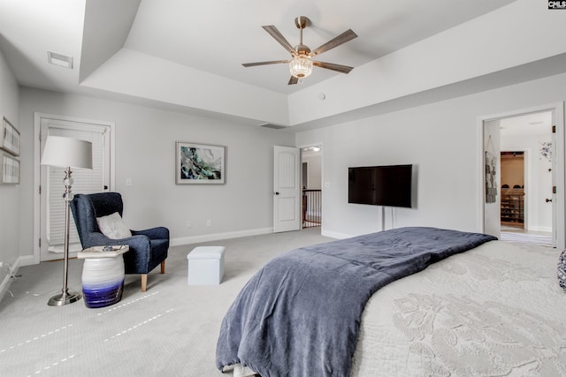 carpeted bedroom with a ceiling fan, a raised ceiling, visible vents, and baseboards