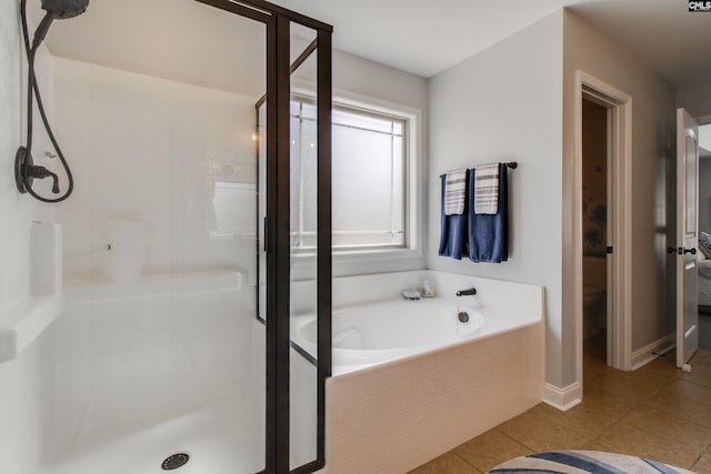 bathroom featuring a stall shower, tile patterned flooring, baseboards, and a garden tub