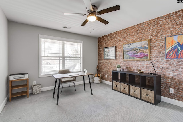 office area with brick wall, visible vents, and light colored carpet