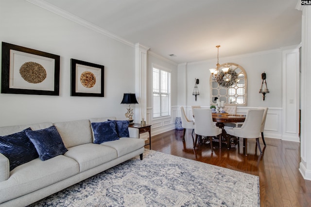 living room featuring a wainscoted wall, a decorative wall, ornamental molding, a chandelier, and hardwood / wood-style flooring