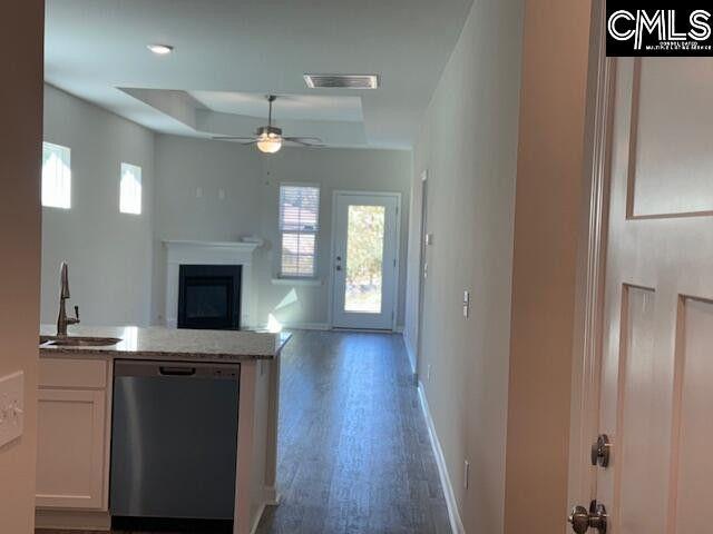 kitchen with visible vents, white cabinets, a sink, dishwasher, and baseboards