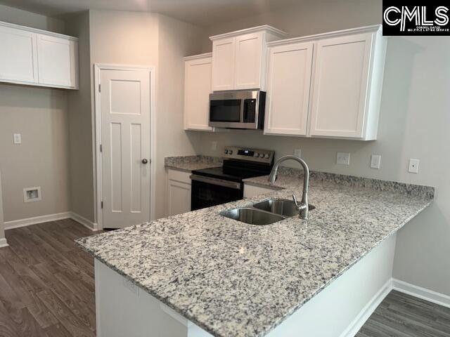 kitchen with stainless steel appliances, white cabinets, a sink, and a peninsula