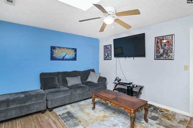 living room featuring a textured ceiling, ceiling fan, wood finished floors, and baseboards