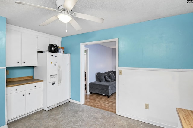 kitchen with a textured ceiling, white refrigerator with ice dispenser, a ceiling fan, white cabinets, and light floors