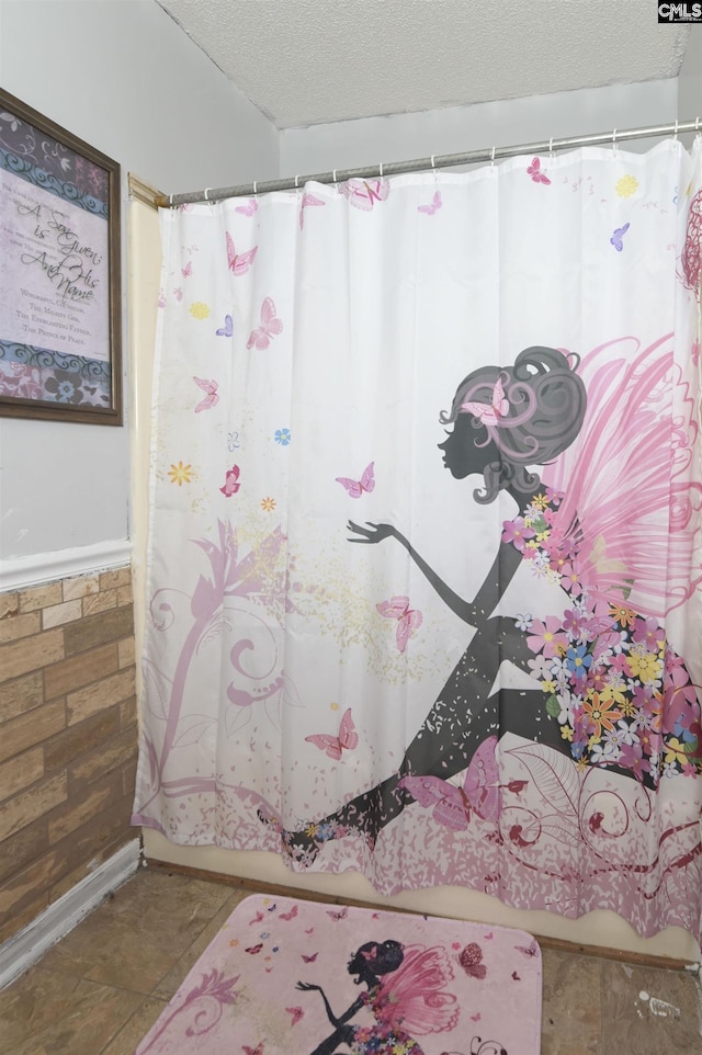 full bathroom with a textured ceiling, a wainscoted wall, and a shower with curtain