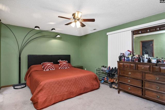 bedroom with carpet floors, visible vents, a textured ceiling, and a ceiling fan