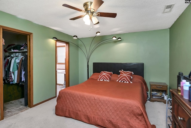 carpeted bedroom featuring a textured ceiling, a spacious closet, a closet, and visible vents