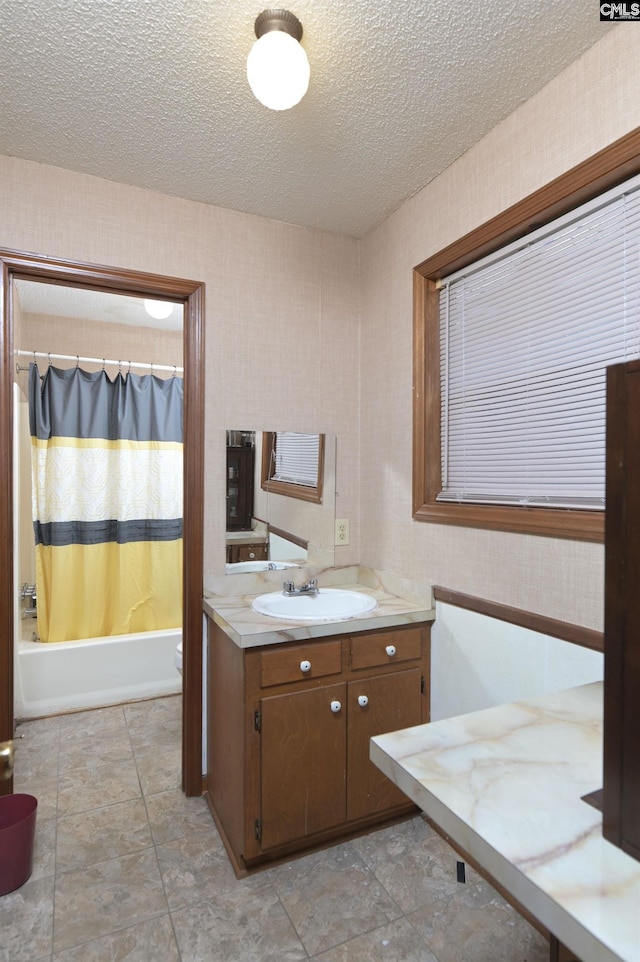 bathroom with a textured ceiling, toilet, vanity, shower / bath combo, and wallpapered walls