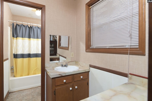 bathroom featuring wallpapered walls, shower / tub combo with curtain, and vanity