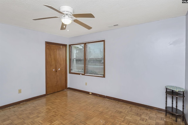 spare room with a ceiling fan, visible vents, a textured ceiling, and baseboards