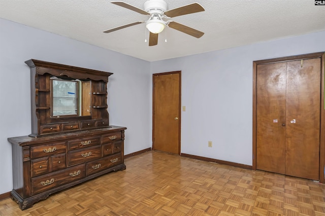 bedroom with a textured ceiling, two closets, a ceiling fan, and baseboards