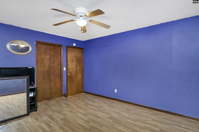 unfurnished bedroom featuring a textured ceiling, wood finished floors, a ceiling fan, and baseboards