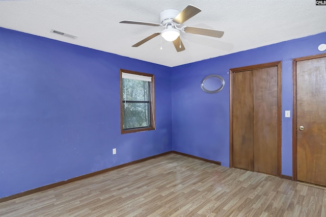 unfurnished bedroom with visible vents, a ceiling fan, a textured ceiling, wood finished floors, and baseboards