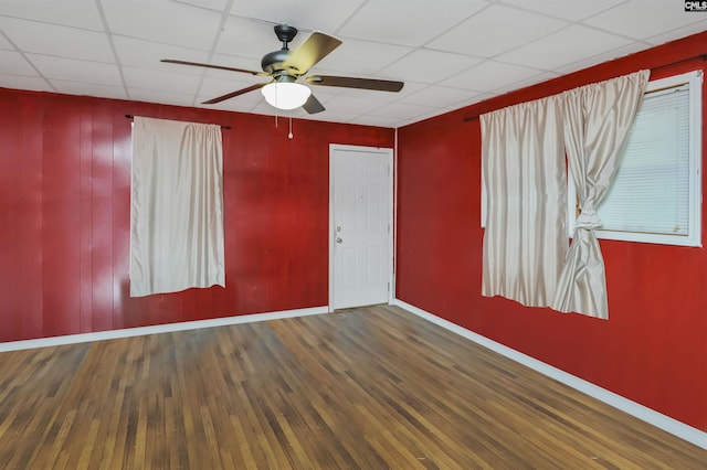 unfurnished room featuring ceiling fan, wood finished floors, a paneled ceiling, and baseboards