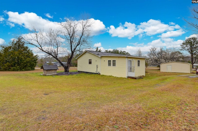 back of house with a yard, an outdoor structure, and a storage shed