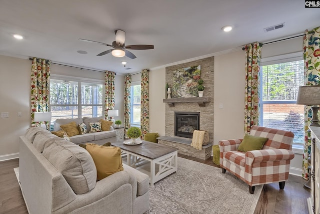 living area with baseboards, visible vents, ornamental molding, wood finished floors, and a fireplace