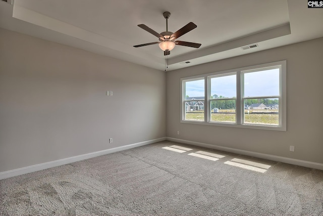 empty room featuring carpet flooring, a raised ceiling, visible vents, and baseboards