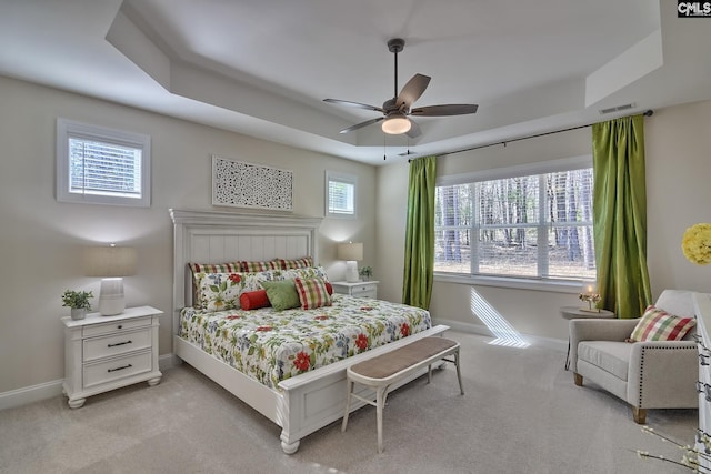 bedroom featuring baseboards, a tray ceiling, visible vents, and light colored carpet