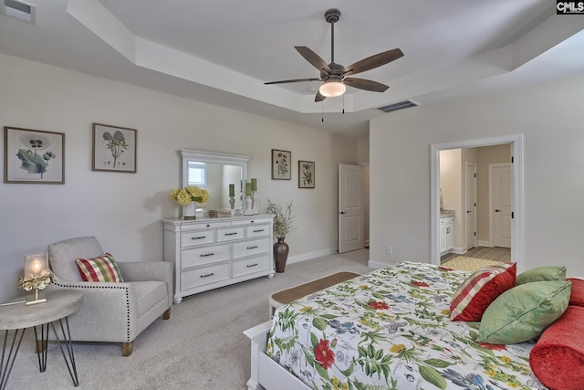 bedroom with light carpet, a tray ceiling, visible vents, and baseboards