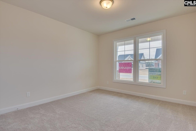 spare room featuring visible vents, light carpet, and baseboards