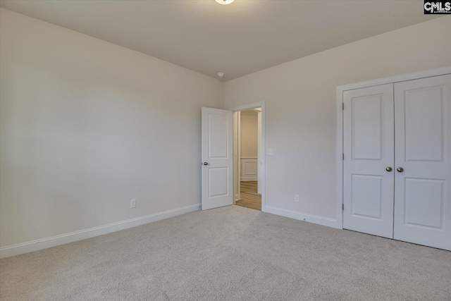 unfurnished bedroom with a closet, carpet, and baseboards