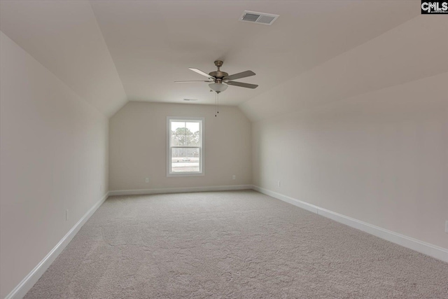 additional living space featuring baseboards, visible vents, vaulted ceiling, and light colored carpet