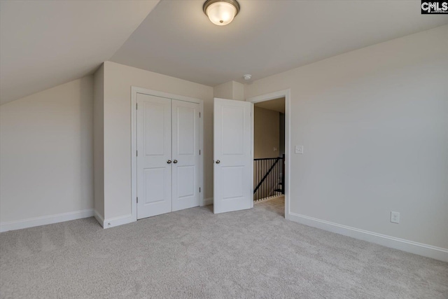 unfurnished bedroom with light carpet, a closet, and baseboards