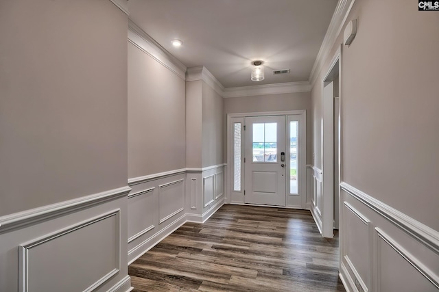 entrance foyer with visible vents, a decorative wall, ornamental molding, dark wood-type flooring, and wainscoting