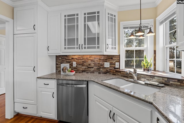 kitchen with a sink, ornamental molding, backsplash, dishwasher, and glass insert cabinets