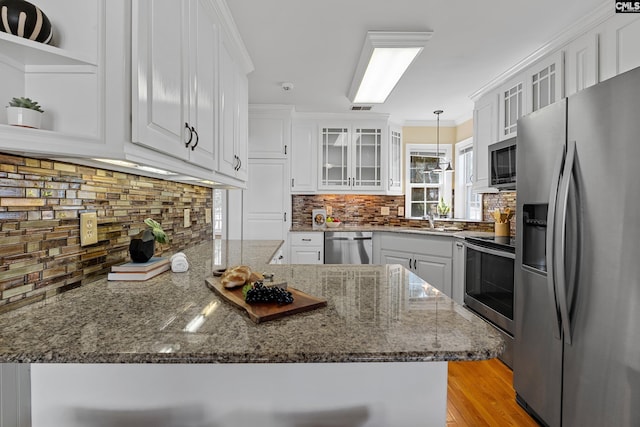 kitchen with appliances with stainless steel finishes, white cabinetry, crown molding, and a peninsula