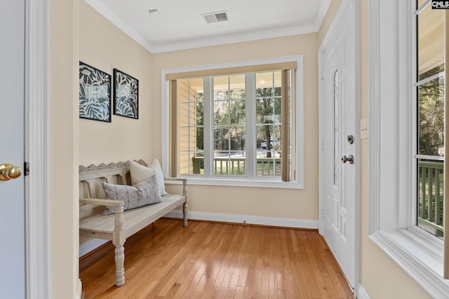 living area with ornamental molding, light wood finished floors, visible vents, and baseboards
